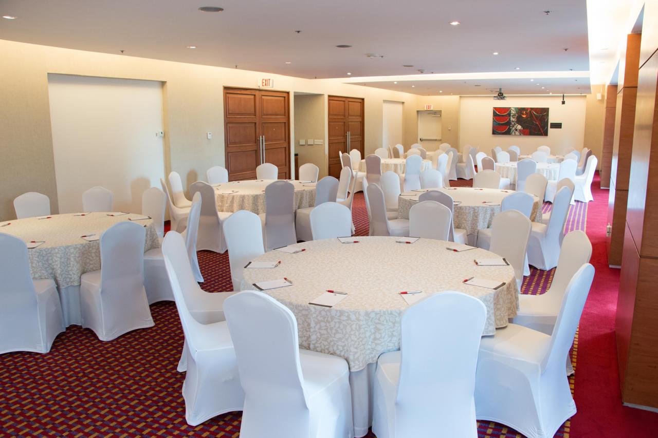 Salón de eventos Rufino Tamayo con mesas redondas y sillas cubiertas de blanco.